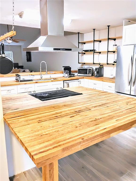 A kitchen features a large wooden island, stainless steel appliances, and open industrial-style shelving — 2012 DOVER COURT, OLDSMAR, FL