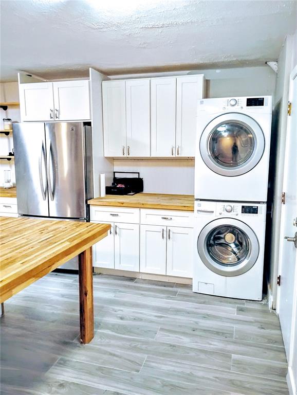 A kitchen features white cabinets, stainless steel appliances, a stacked washer-dryer, and wood countertops — 2012 DOVER COURT, OLDSMAR, FL