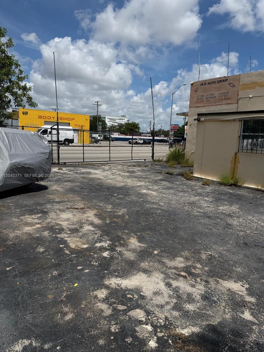 An outdoor paved lot sits between a yellow body shop and a beige building — 3445 NW 27th Ave, Miami FL 33142, MIAMI, FL