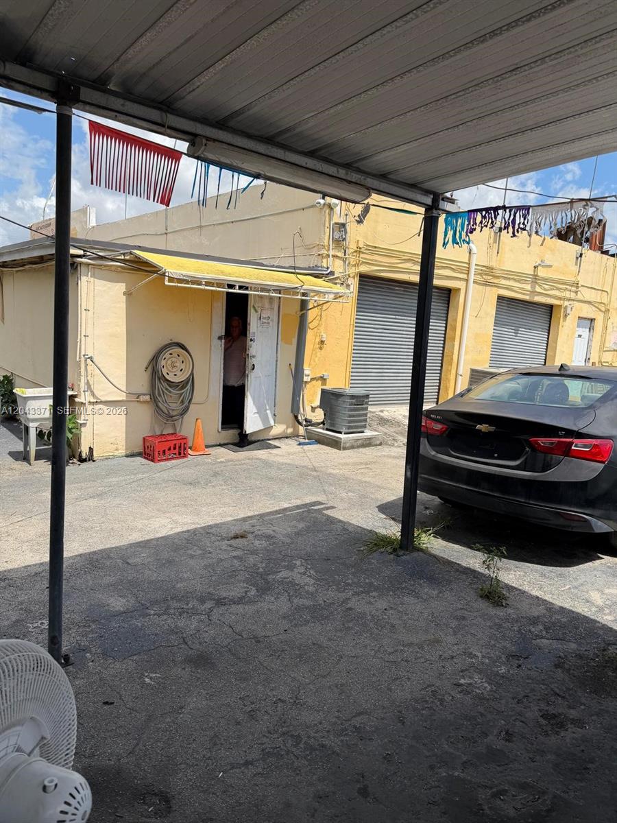 A paved parking area sits in front of a yellow building with a metal awning — 3445 NW 27th Ave, Miami FL 33142, MIAMI, FL