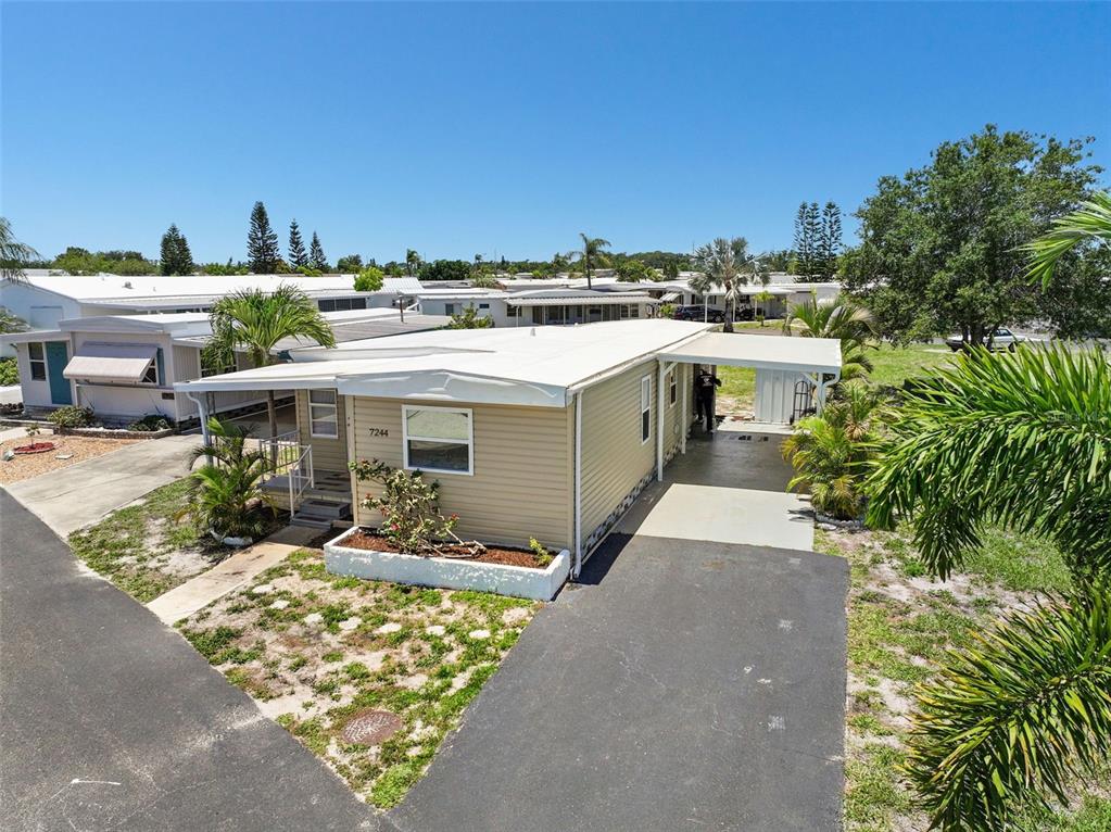 A tan mobile home with a white roof, carport, and small front garden — 7244 MOUNT FAIRFIELD ROAD NE UNIT 530, ST PETERSBURG, FL