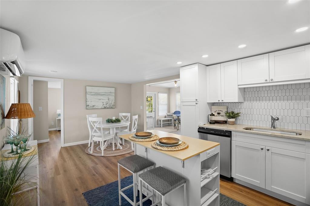 A kitchen with white cabinets, a small island, and an adjacent dining area with wood flooring — 7244 MOUNT FAIRFIELD ROAD NE UNIT 530, ST PETERSBURG, FL