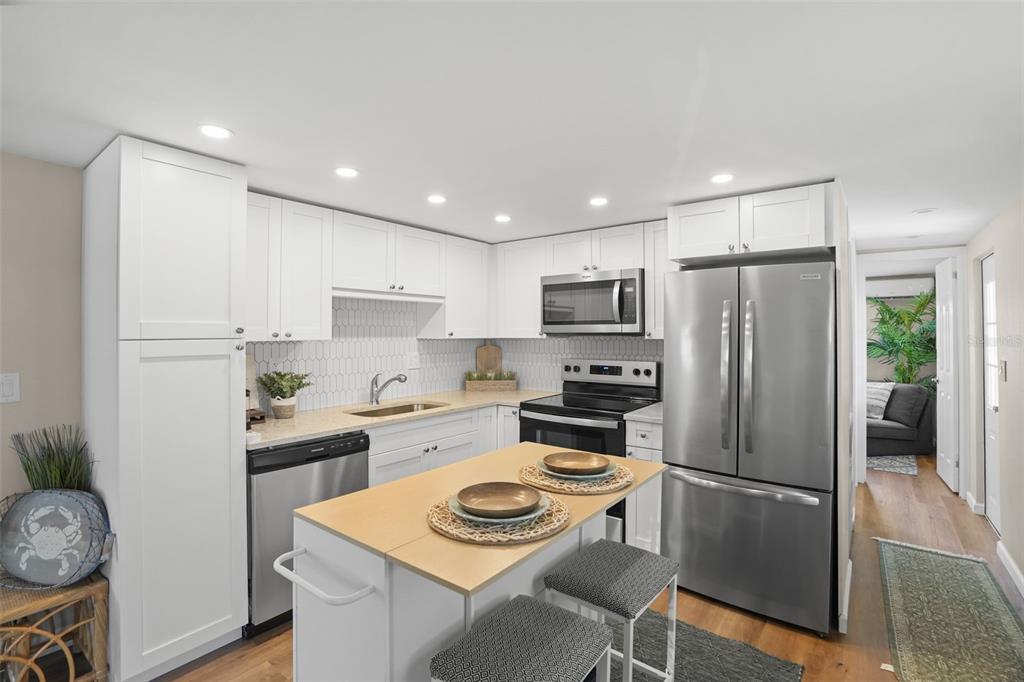 A kitchen features white cabinets, stainless steel appliances, a center island, and light-colored countertops — 7244 MOUNT FAIRFIELD ROAD NE UNIT 530, ST PETERSBURG, FL