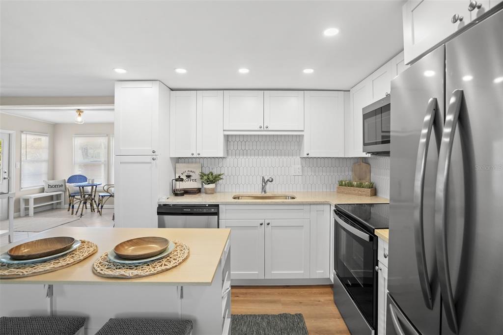 A kitchen features white cabinets, a light countertop, stainless steel appliances, and a central island — 7244 MOUNT FAIRFIELD ROAD NE UNIT 530, ST PETERSBURG, FL