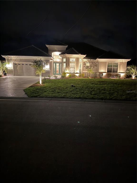 A single-story house with a tiled roof and exterior landscape lighting at night — 1745 N COMMONWEALTH WAY, HERNANDO, FL