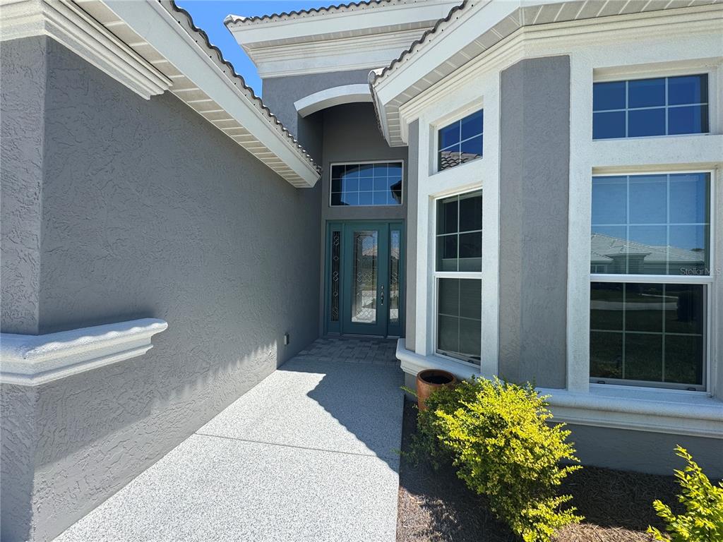A gray stucco house exterior features a teal front door and a concrete walkway — 1745 N COMMONWEALTH WAY, HERNANDO, FL