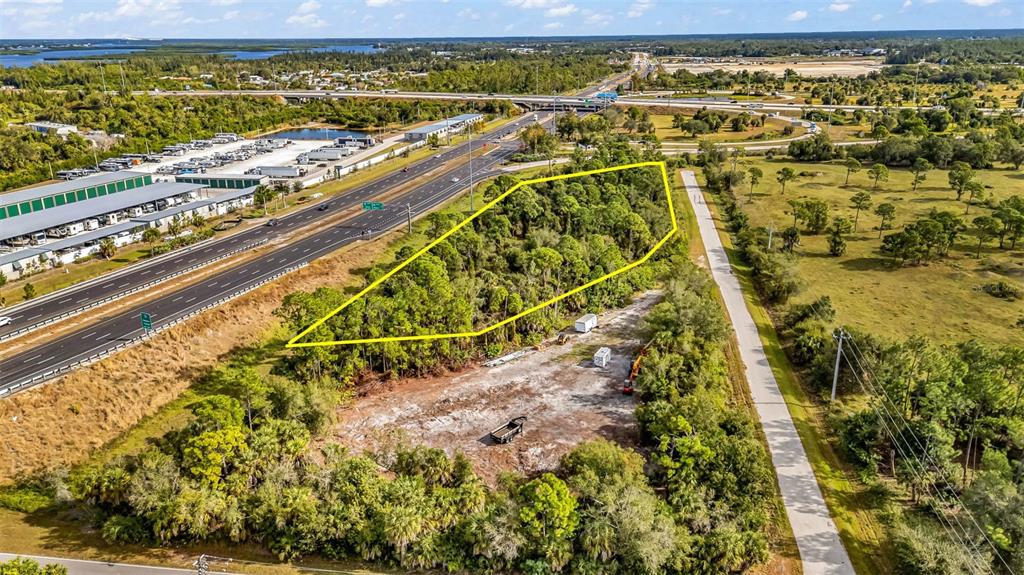 An aerial view shows a wooded lot outlined in yellow next to a highway — Unnamed US17 I75 EXIT 164 STREET, PUNTA GORDA, FL