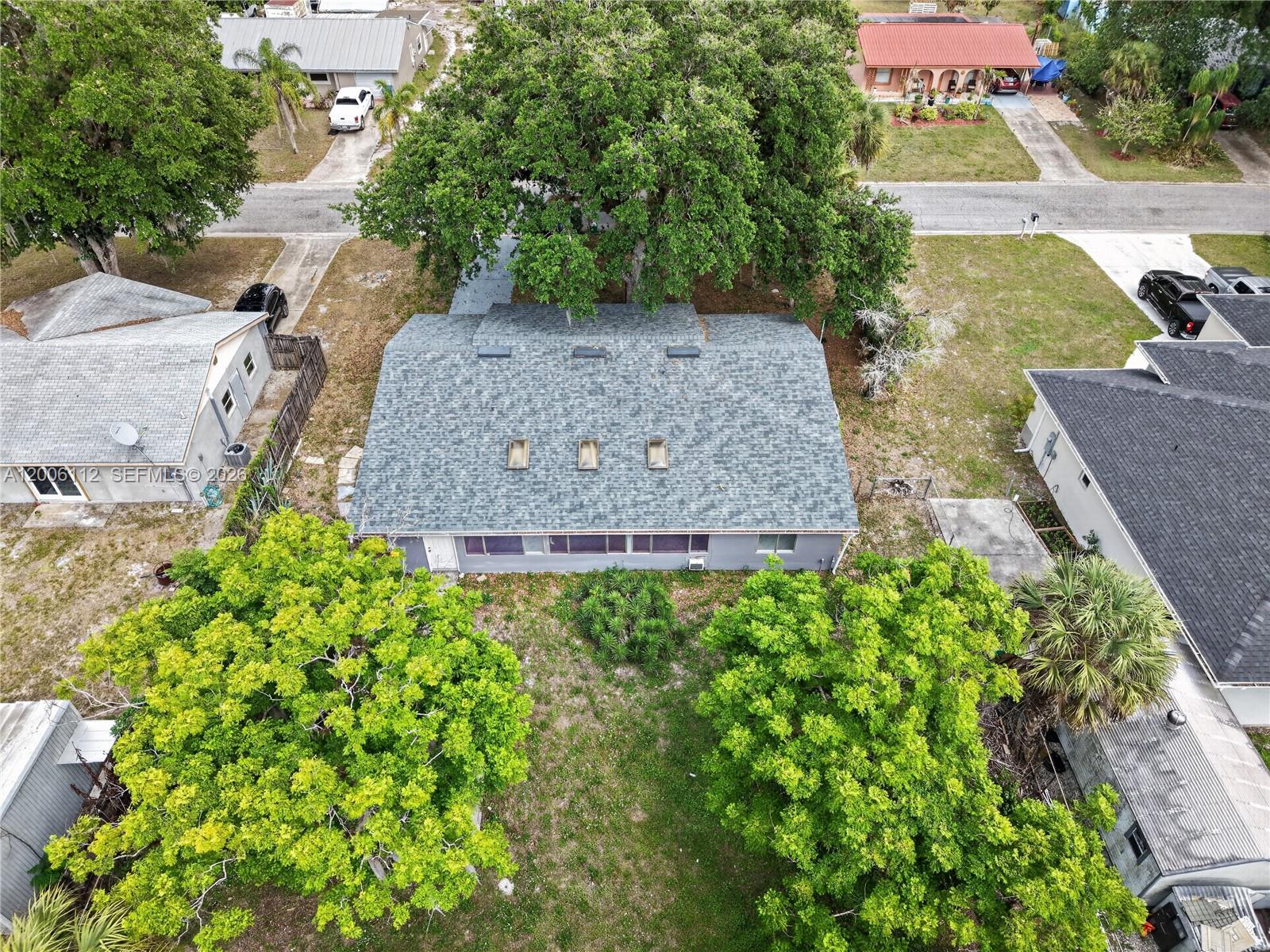 An aerial view shows a single-story house with a gray shingled roof and three skylights — 4030 SCHOOL CIR, La Belle FL 33935, LA BELLE, FL