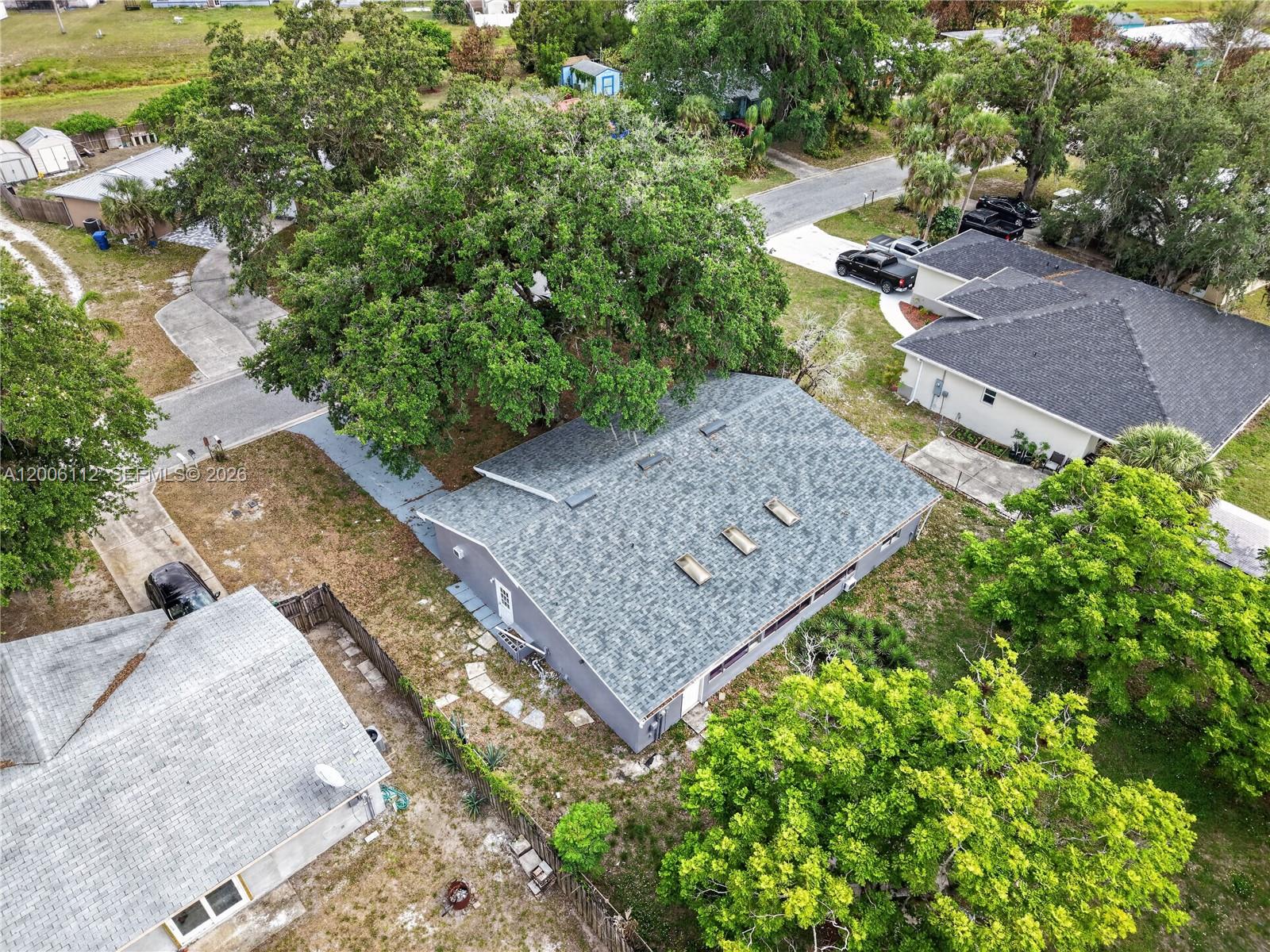 An aerial view shows a gray house with a shingled roof and multiple skylights — 4030 SCHOOL CIR, La Belle FL 33935, LA BELLE, FL