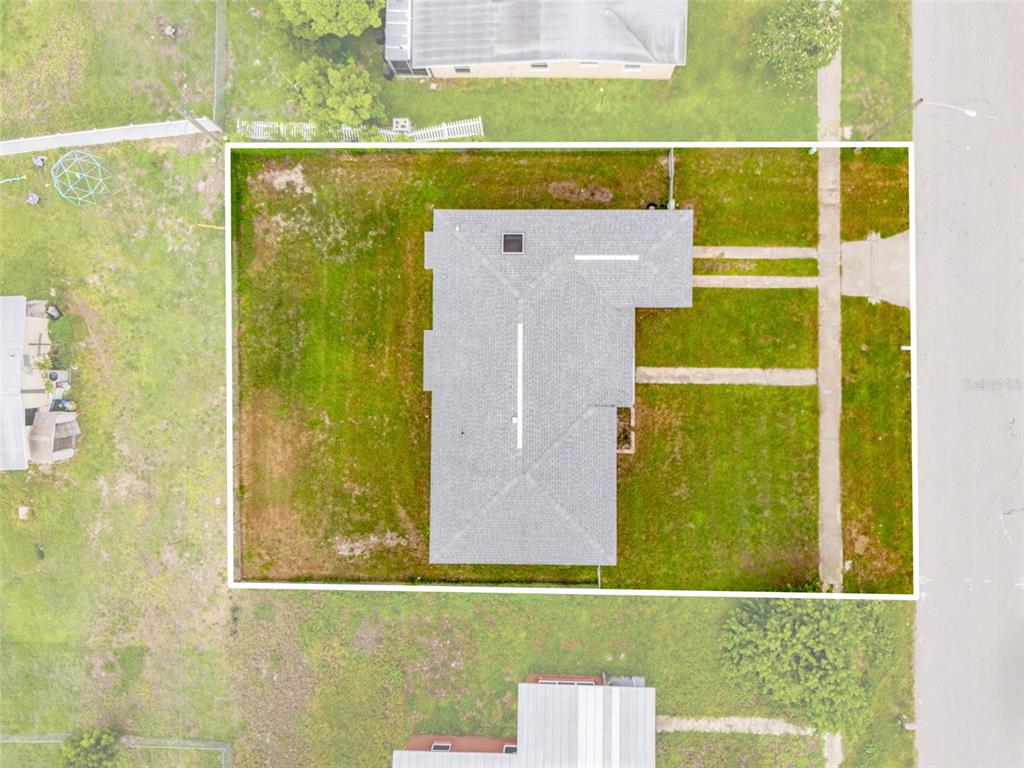 An aerial view shows a house with a gray roof centered on a grassy lot — 21928 BEVERLY AVENUE, PORT CHARLOTTE, FL