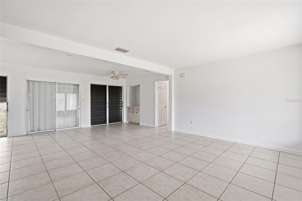 A spacious room with white walls, light-colored tile flooring, and sliding glass doors — 21928 BEVERLY AVENUE, PORT CHARLOTTE, FL