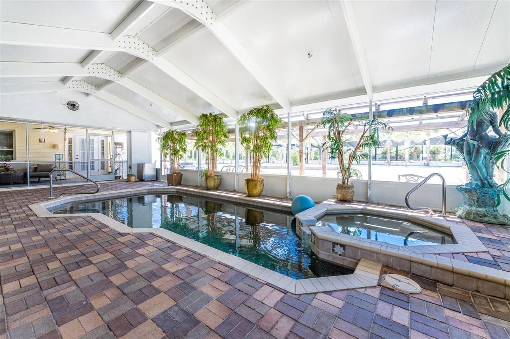 An indoor pool and hot tub area with brick pavers and potted plants — 668 PALOMINO TRAIL, ENGLEWOOD, FL