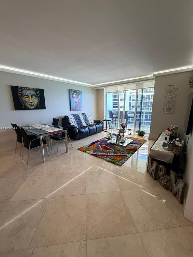 A living and dining area features tile floors, a colorful rug, and a balcony view — 1830 S Ocean Dr # 3810, Hallandale Beach FL 33009, HALLANDALE BEACH, FL