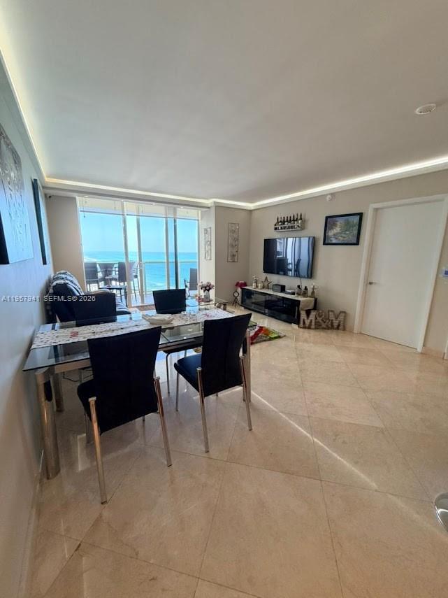A dining area with a glass table and black chairs overlooks the ocean through windows — 1830 S Ocean Dr # 3810, Hallandale Beach FL 33009, HALLANDALE BEACH, FL