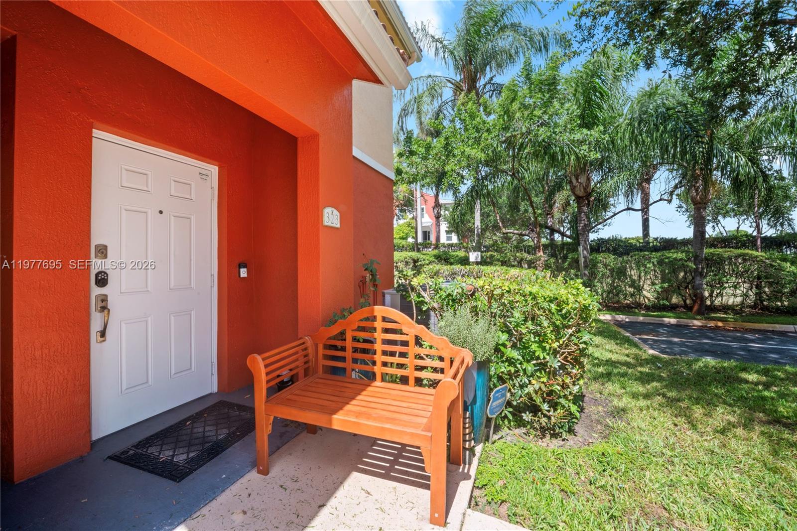A wooden bench sits on a concrete porch in front of a bright orange house — 3335 Palomino Dr # 3, Davie FL 33024, DAVIE, FL