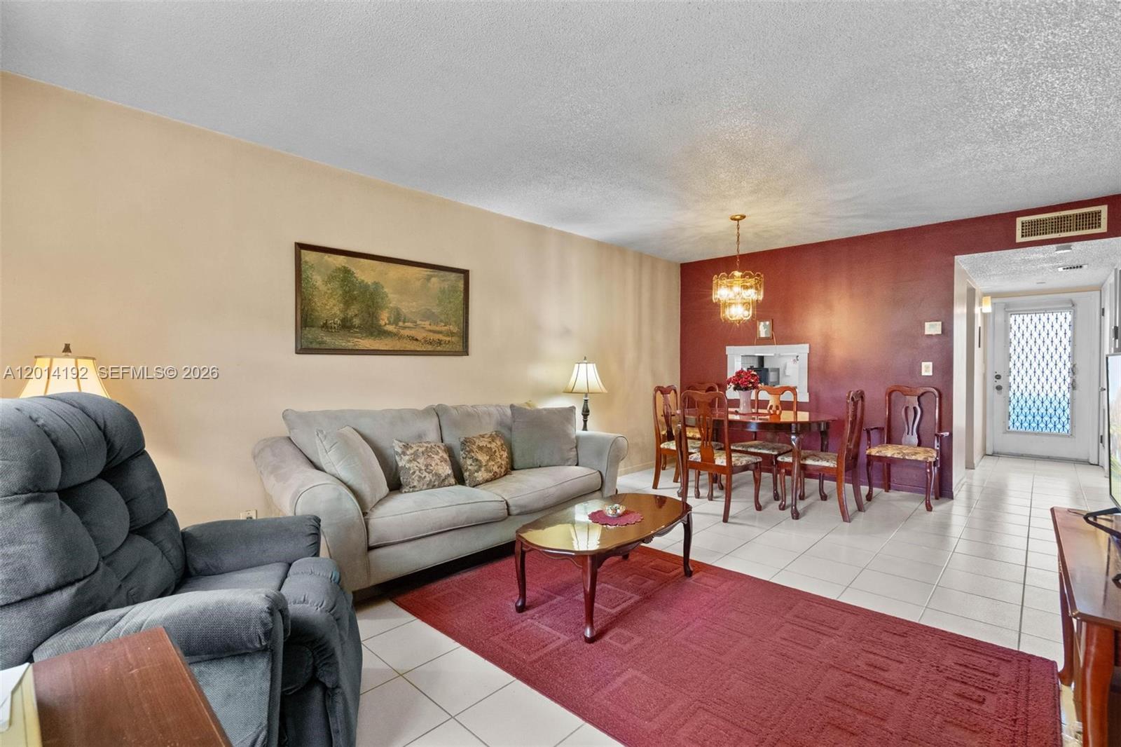 A living and dining area features tile floors, a red accent wall, and a rug — 100 Berkley Rd # 106, Hollywood FL 33024, HOLLYWOOD, FL