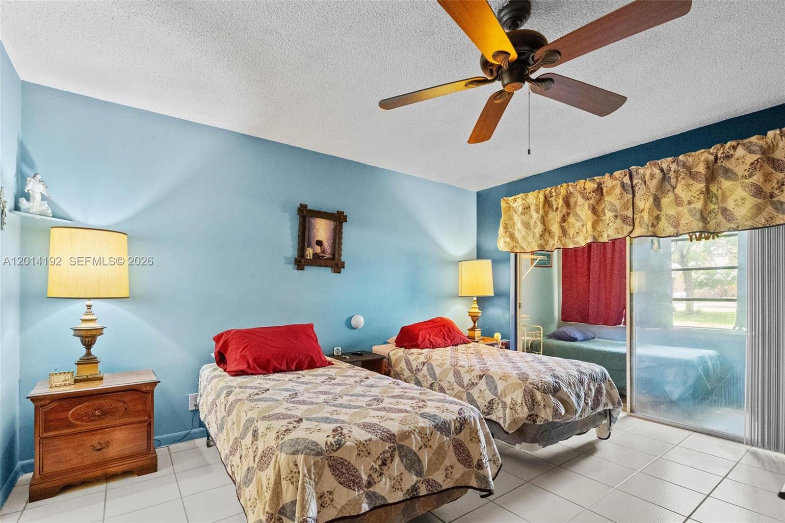 A bedroom features two twin beds, blue walls, tile flooring, and a ceiling fan — 100 Berkley Rd # 106, Hollywood FL 33024, HOLLYWOOD, FL