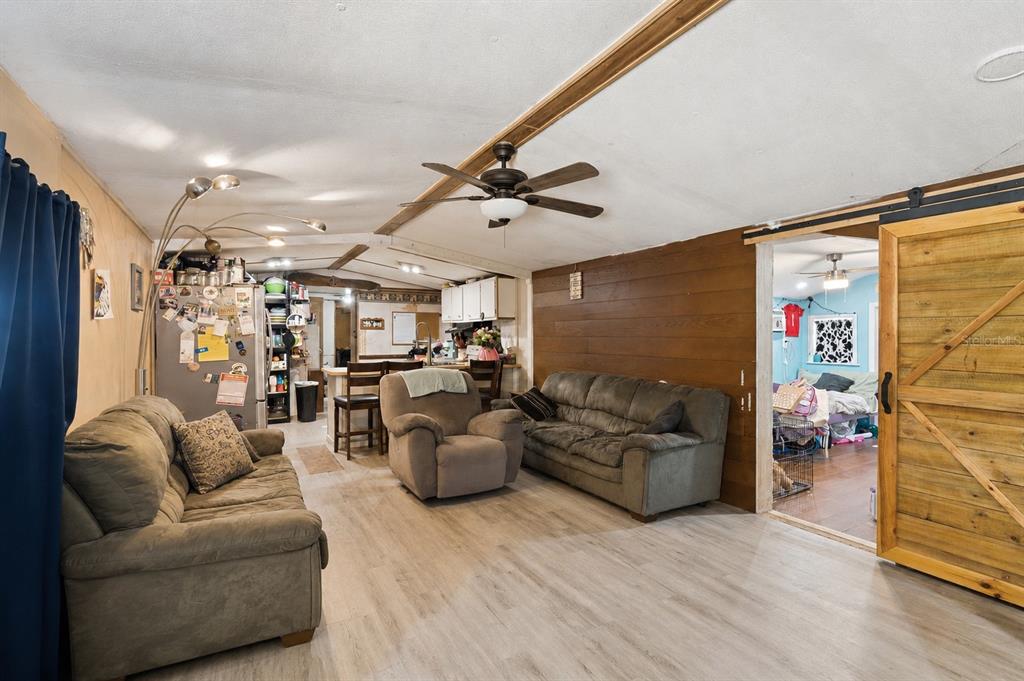A single-story manufactured home sits behind a fenced yard with a flagpole and trees — 10927 LUANA DRIVE, LEESBURG, FL
