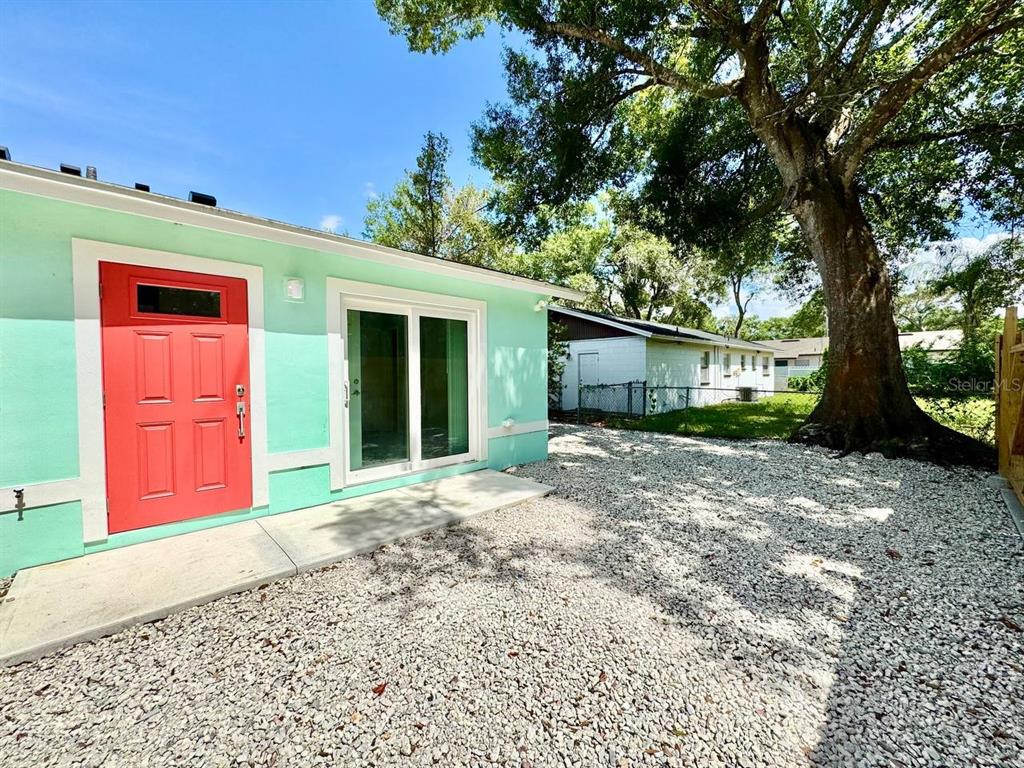A mint green exterior wall features a bright red door and a sliding glass door — 4306 PORPOISE DRIVE UNIT A, TAMPA, FL