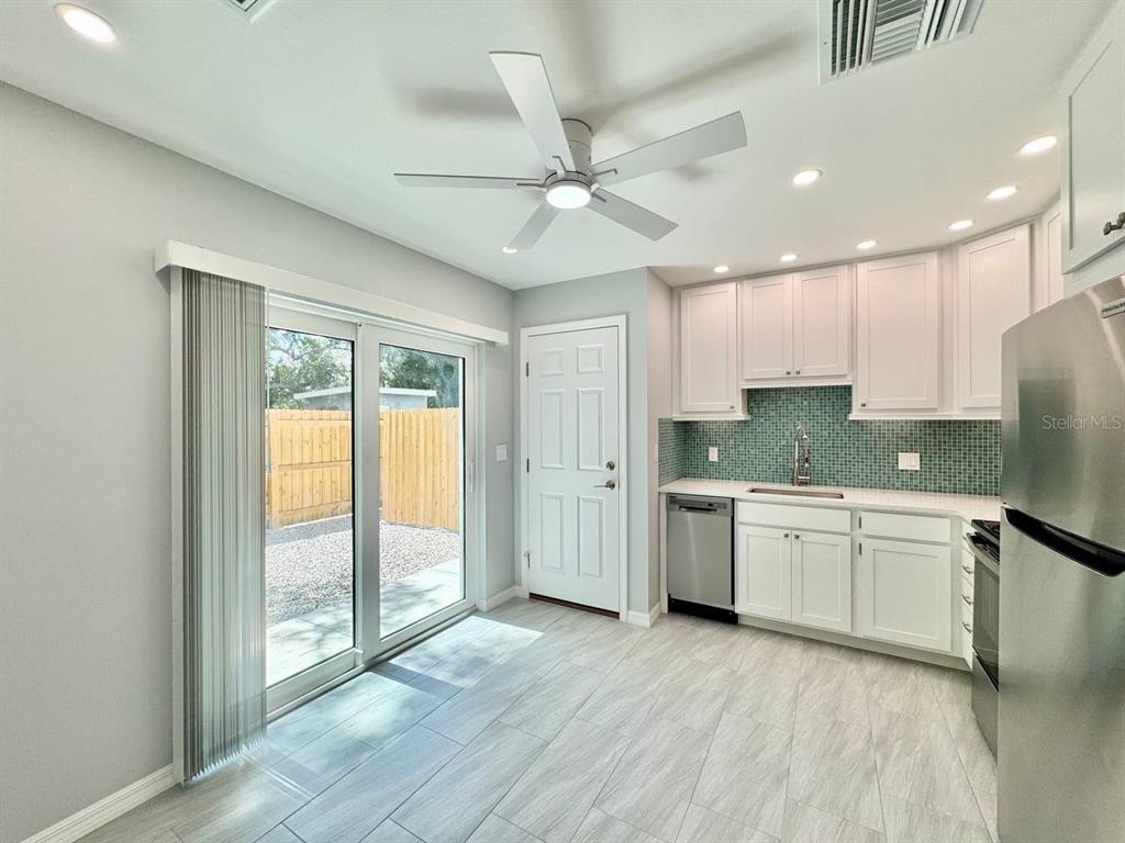 A kitchen with white cabinets, a teal tile backsplash, and a sliding glass door — 4306 PORPOISE DRIVE UNIT A, TAMPA, FL