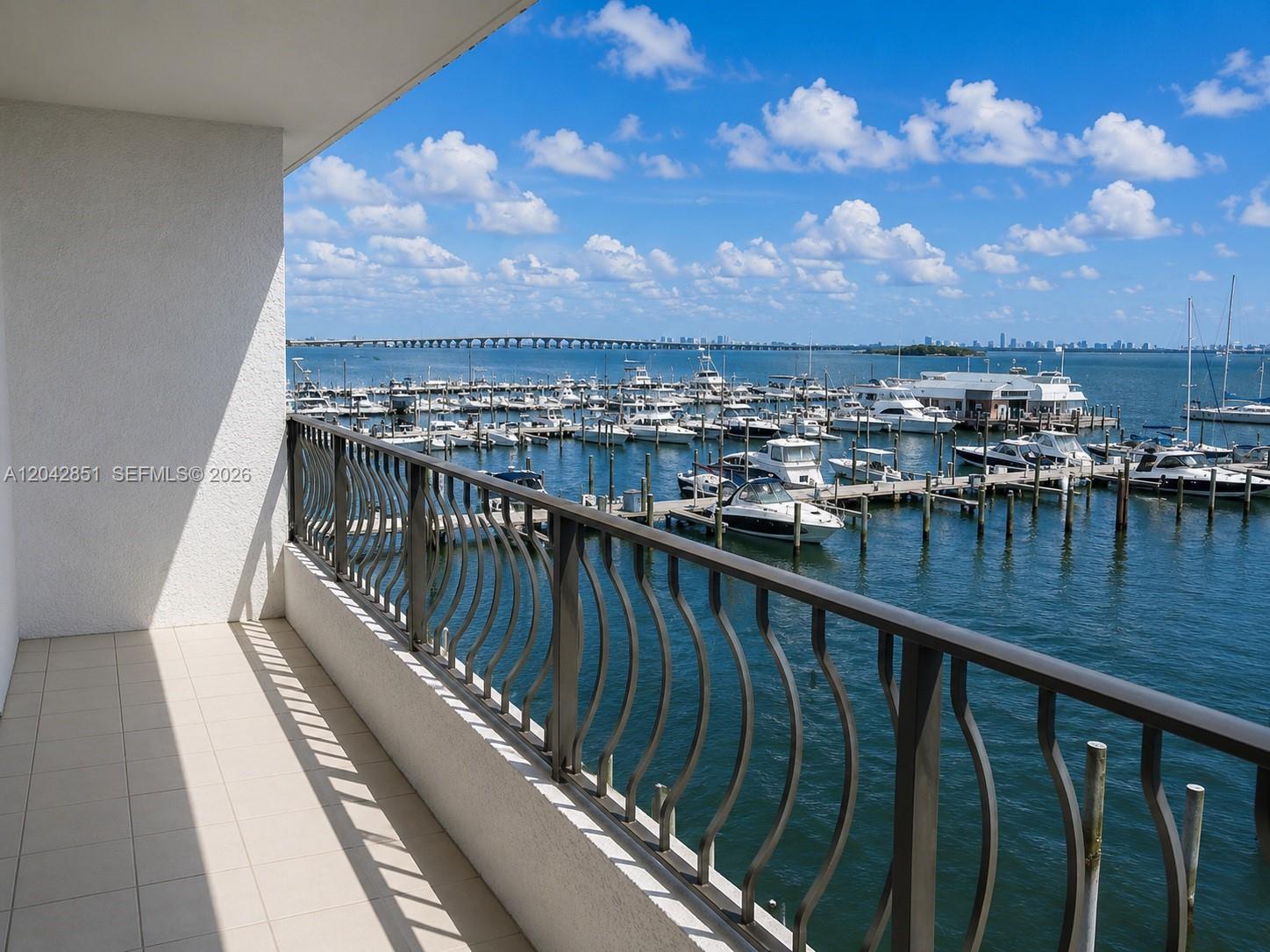 A balcony with a metal railing overlooks a marina filled with boats and a bridge — 555 NE 15th St # 403, Miami FL 33132, MIAMI, FL