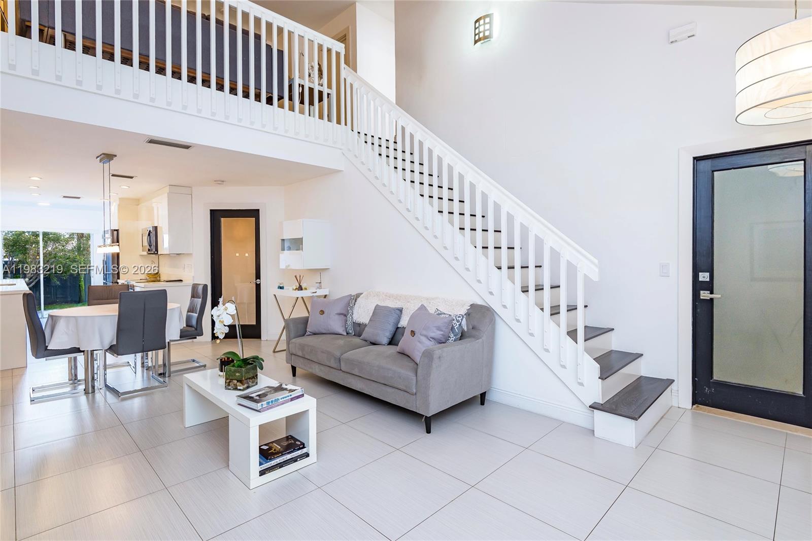 A living room features a grey sofa, a staircase, and an adjacent dining area — 370 SE 2nd Ave # G3, Deerfield Beach FL 33441, DEERFIELD BEACH, FL