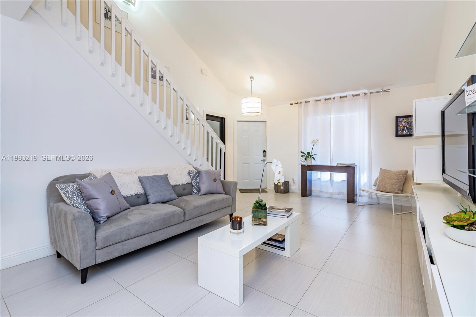 A living room features a grey sofa, white coffee table, staircase, and tile flooring — 370 SE 2nd Ave # G3, Deerfield Beach FL 33441, DEERFIELD BEACH, FL