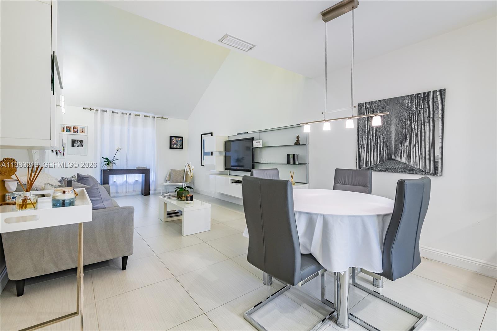 A bright living and dining area features vaulted ceilings, white tile floors, and modern furniture — 370 SE 2nd Ave # G3, Deerfield Beach FL 33441, DEERFIELD BEACH, FL