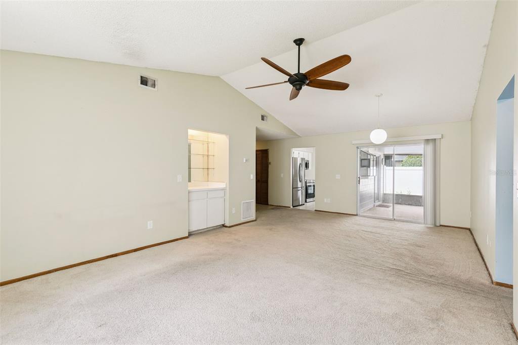 A living room with beige carpet, a vaulted ceiling, a ceiling fan, and a wet bar — 3455 JUJUBE DRIVE, ORLANDO, FL