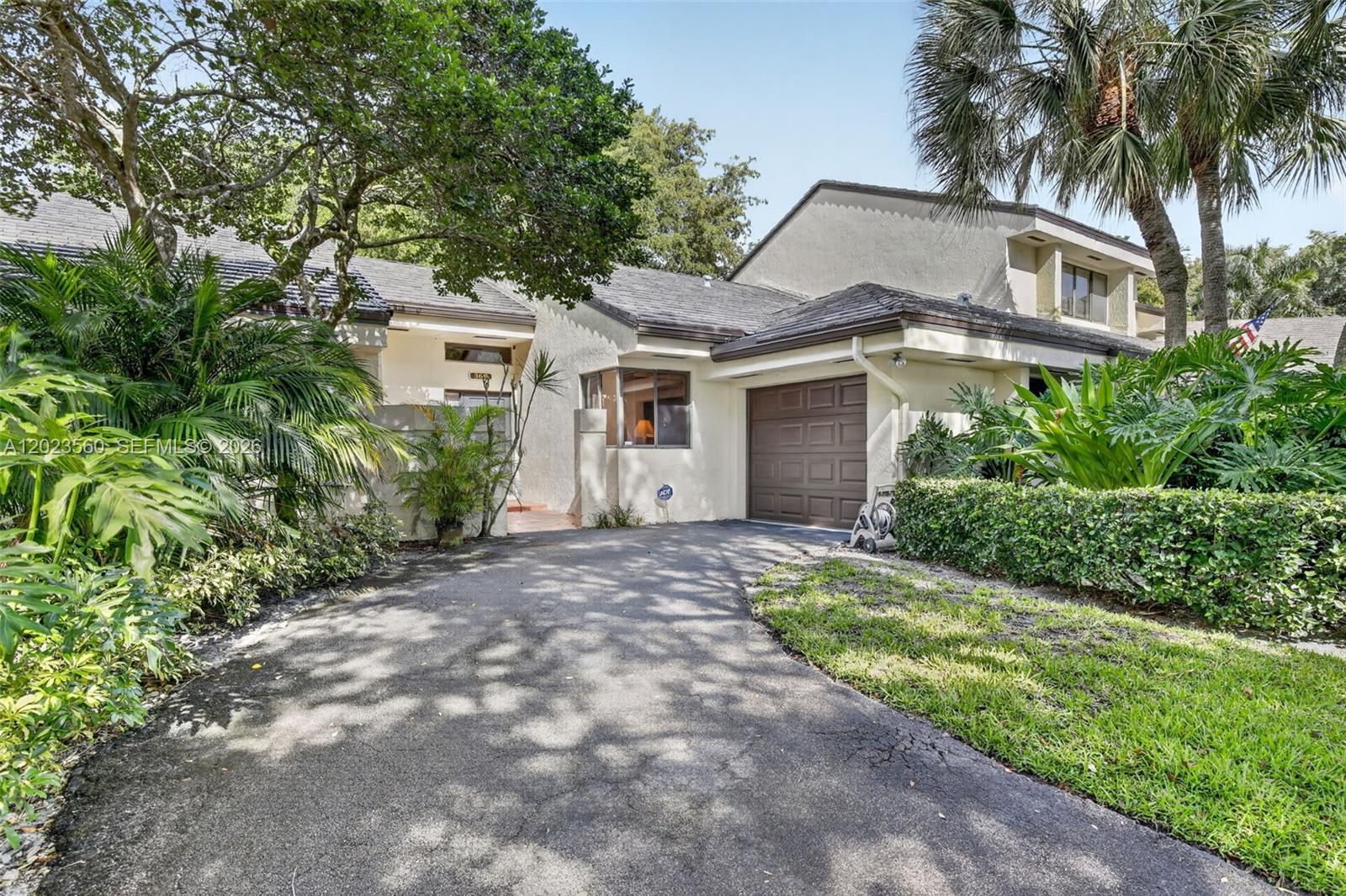A single-story house with a brown garage door, paved driveway, and lush tropical landscaping — 369 NW 97th Ave, Plantation FL 33324, PLANTATION, FL