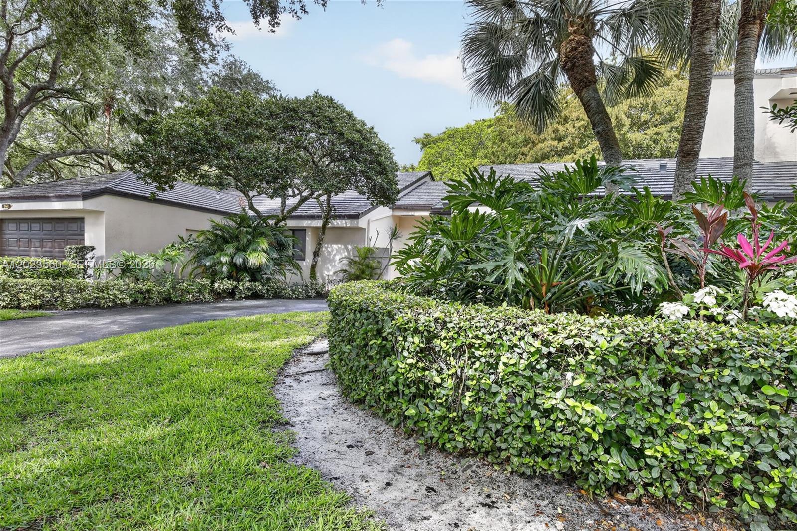 A single-story house with a garage, a paved driveway, and lush landscaping in the front yard — 369 NW 97th Ave, Plantation FL 33324, PLANTATION, FL