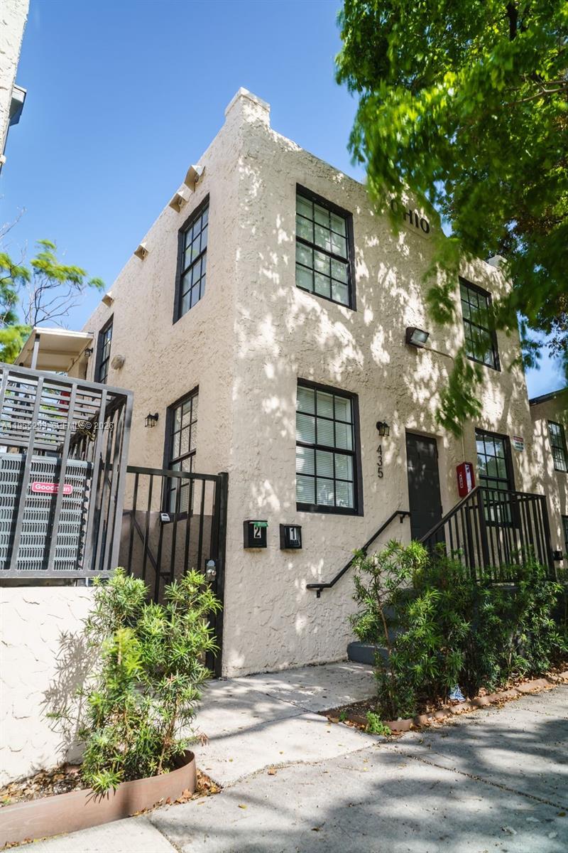 A two-story stucco building with black-framed windows and a metal staircase leading to the entrance — 1068 NW 5th St, Miami FL 33128, MIAMI, FL