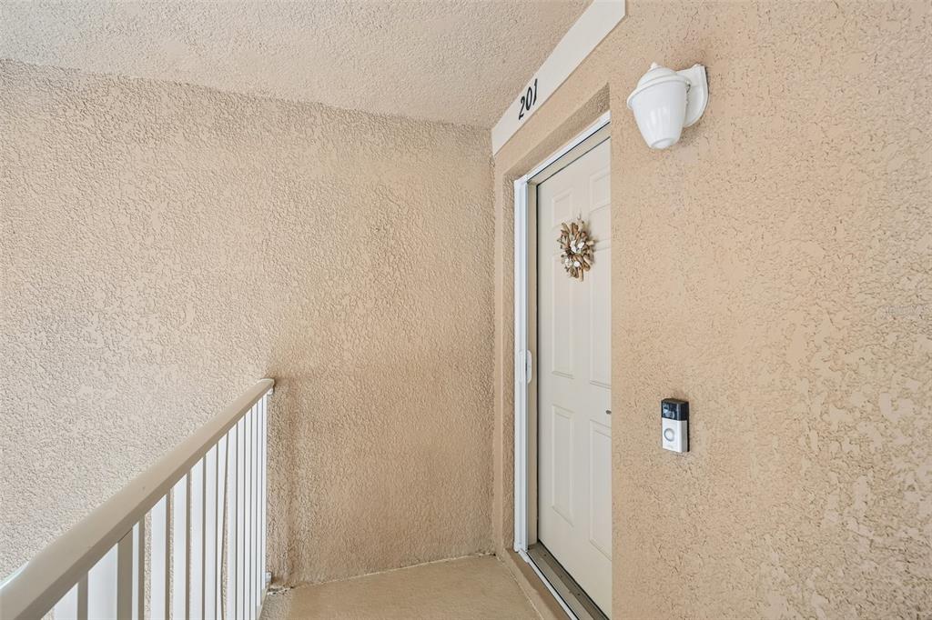 A beige stucco exterior wall features a white door labeled 201 with a wall sconce — 1003 FAIRWAYCOVE LANE UNIT 201, BRADENTON, FL