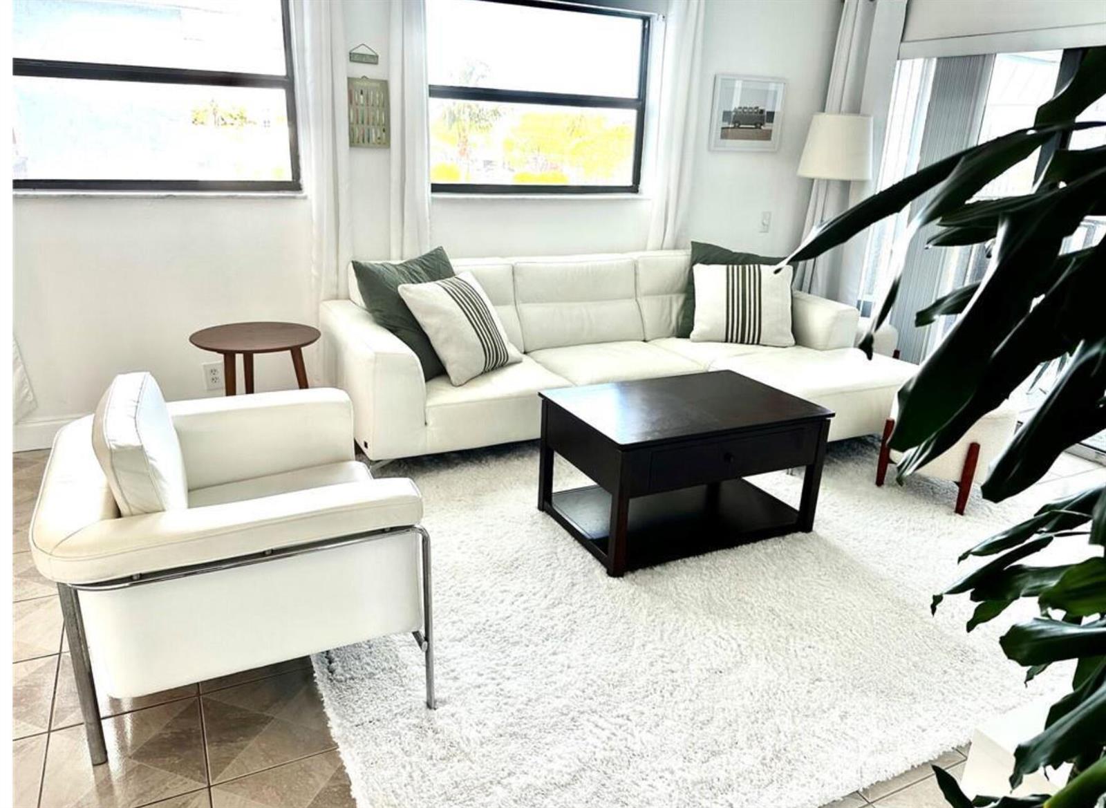 A living room features a white sofa, a matching armchair, and a dark coffee table — 1975 SE 3rd Street # 403, Deerfield Beach FL 33441, DEERFIELD BEACH, FL