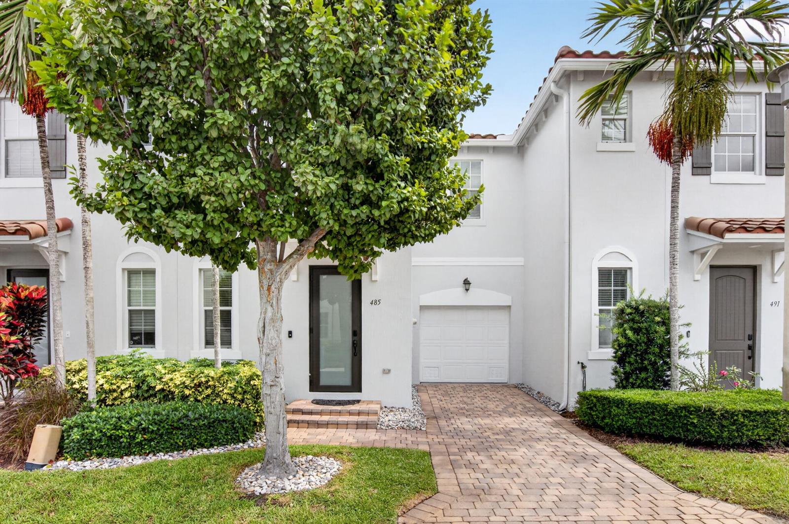 A white two-story townhouse features a paved driveway, a single-car garage, and a front tree — 485 Graham Place, Boynton Beach FL 33435, BOYNTON BEACH, FL