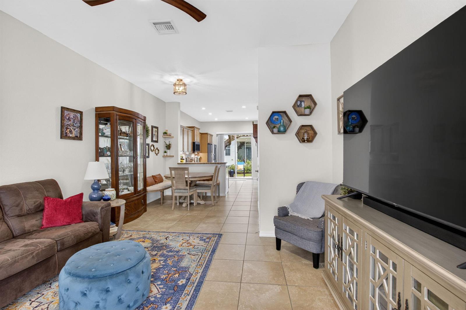 A living room with tile floors, a brown sofa, a television, and a dining area — 485 Graham Place, Boynton Beach FL 33435, BOYNTON BEACH, FL