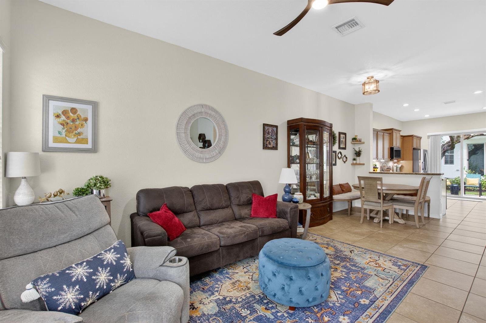 A living room with a brown sofa, gray recliner, blue ottoman, and an open kitchen — 485 Graham Place, Boynton Beach FL 33435, BOYNTON BEACH, FL