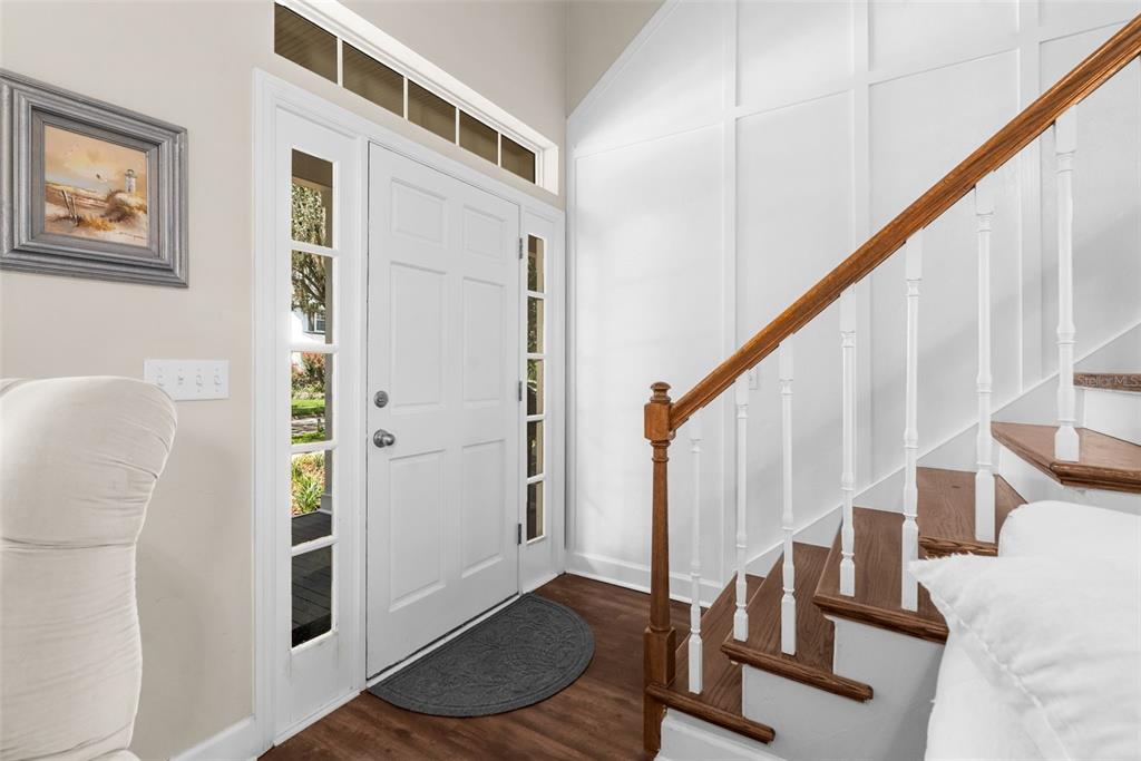 An entryway features a white front door, a wooden staircase, and white board-and-batten wall paneling — 13207 SW 2ND AVENUE, NEWBERRY, FL