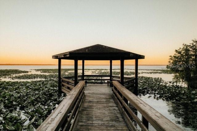 A wooden pier leads to a gazebo overlooking a lake filled with lily pads at sunset — 13821 SE 202ND TERRACE, HAWTHORNE, FL