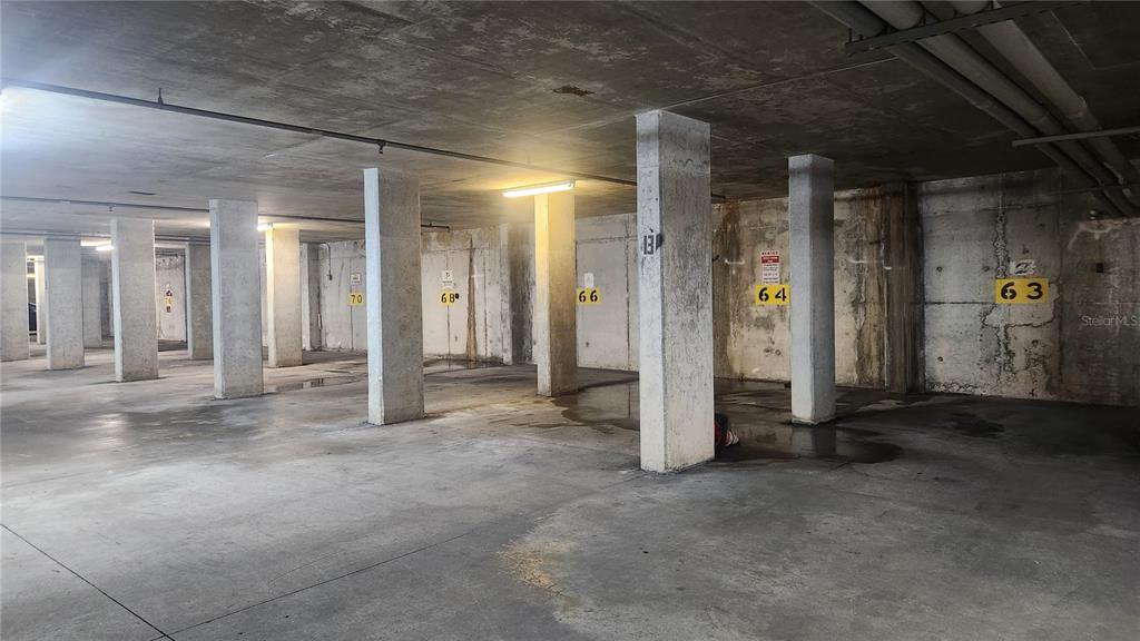 A concrete parking garage features numbered parking spaces separated by support pillars — 101 PALM HARBOR PARKWAY UNIT P066, PALM COAST, FL