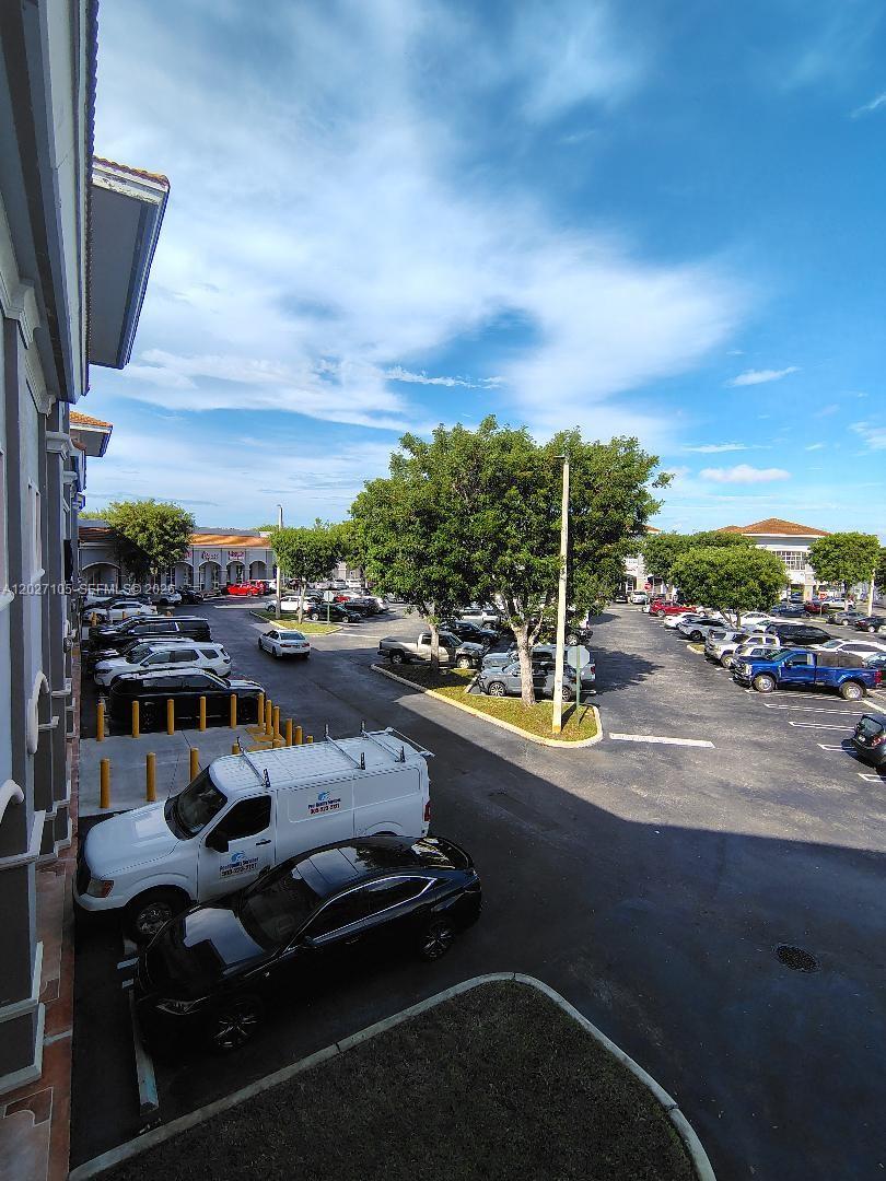 An elevated view of a parking lot with several vehicles and trees in front of buildings — 14285 SW 42nd St # 211, Miami FL 33175, MIAMI, FL