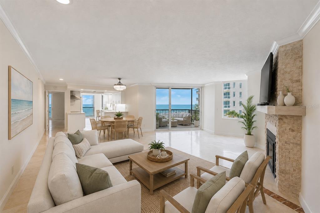 A bright, open-concept living room features a sectional sofa, stone fireplace, and ocean views — 1600 GULF BOULEVARD UNIT 414, CLEARWATER, FL