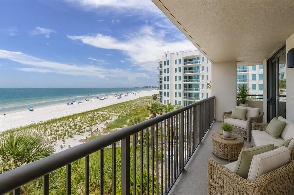 A balcony with wicker furniture overlooks a sandy beach and the ocean — 1600 GULF BOULEVARD UNIT 414, CLEARWATER, FL