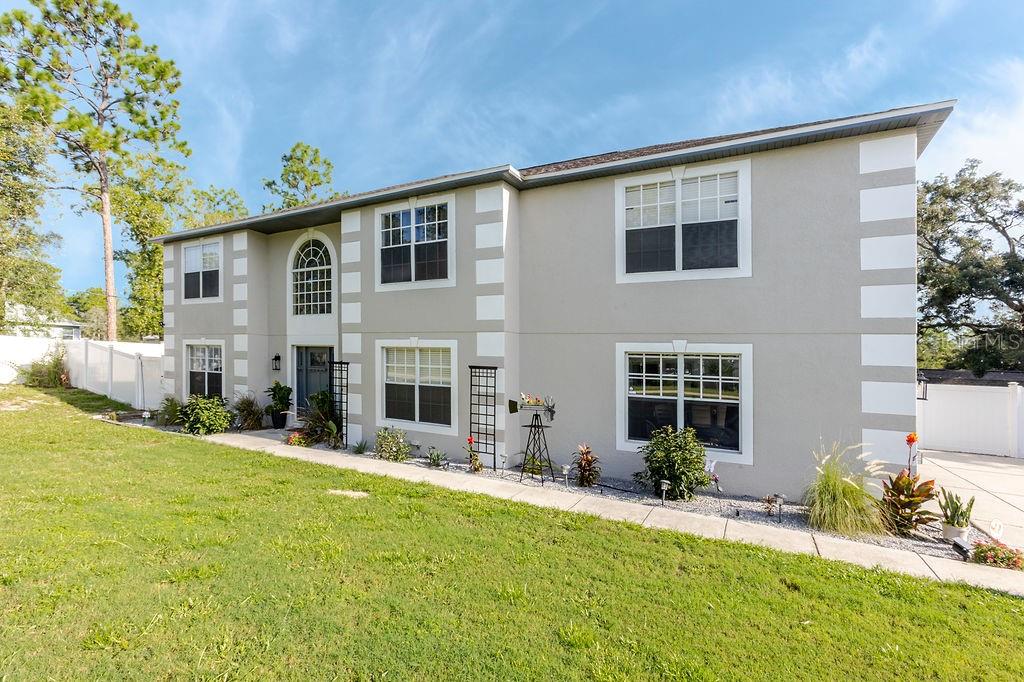 A two-story house with light-colored stucco walls, white corner accents, and a front entryway — 11083 MAYBIRD AVENUE, WEEKI WACHEE, FL