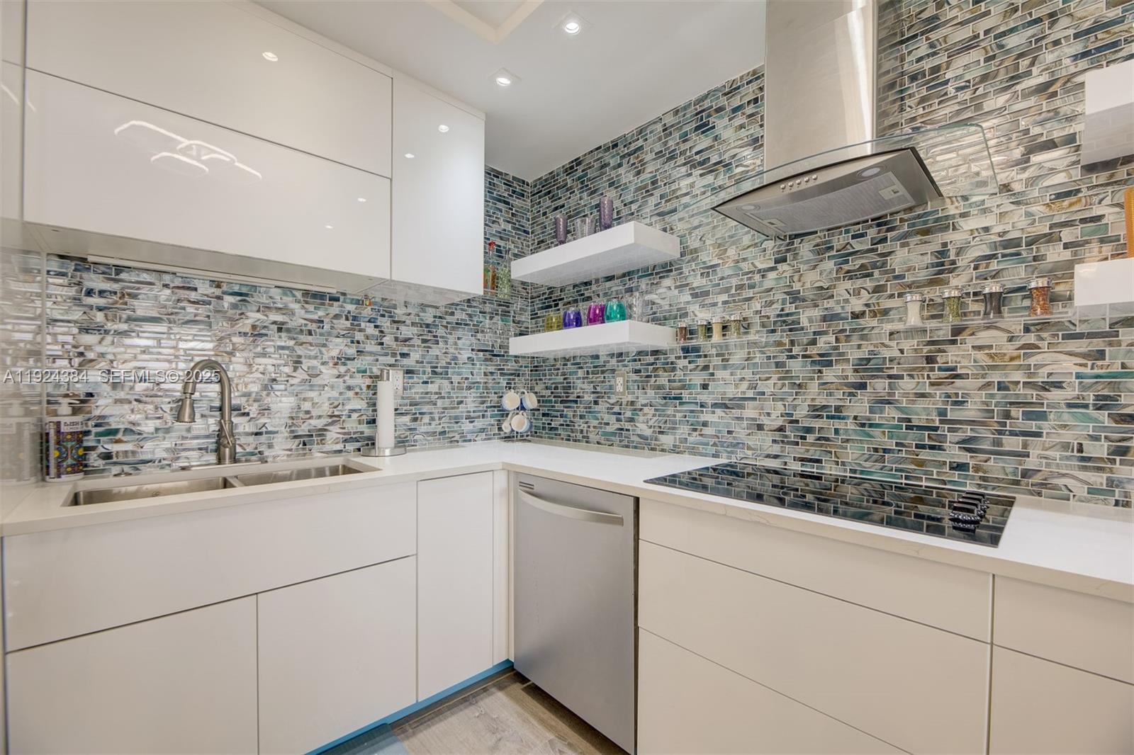 A modern kitchen features white cabinets, a mosaic tile backsplash, and stainless steel appliances — 3725 S Ocean Dr # 601, Hollywood FL 33019, HOLLYWOOD, FL
