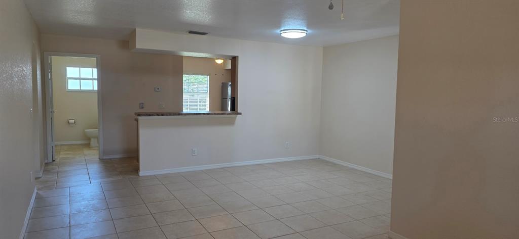 An open-concept living area features light-colored tile flooring, a breakfast bar, and a kitchen view — 26201 EXPLORER ROAD UNIT 5, PUNTA GORDA, FL