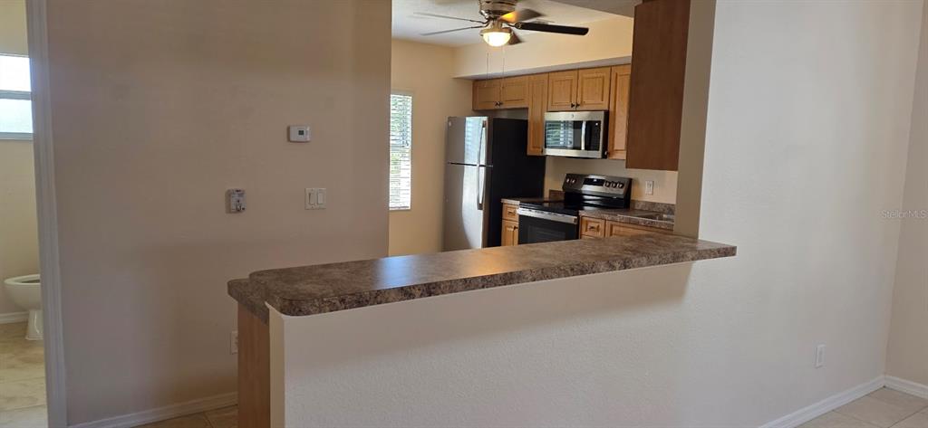 A kitchen with wood cabinets and stainless steel appliances overlooks a breakfast bar — 26201 EXPLORER ROAD UNIT 5, PUNTA GORDA, FL