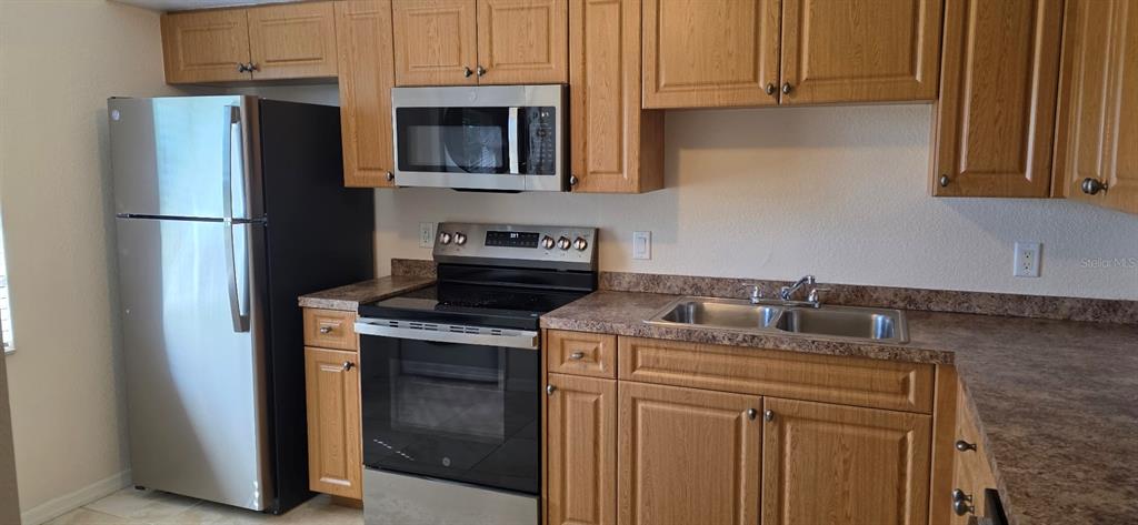 A kitchen features stainless steel appliances, wood cabinets, and brown laminate countertops — 26201 EXPLORER ROAD UNIT 5, PUNTA GORDA, FL