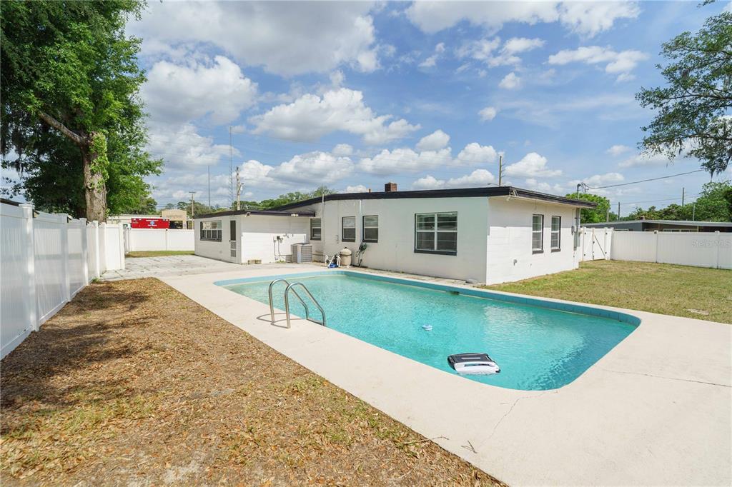 A backyard features a rectangular swimming pool, a white house, and a white vinyl fence — 3523 SE 6TH STREET, OCALA, FL