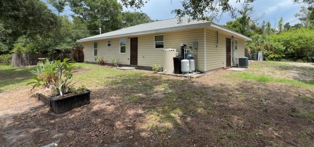 A gravel driveway leads toward a light-colored house surrounded by trees and dense vegetation — 2249 WOODMERE ROAD, VENICE, FL